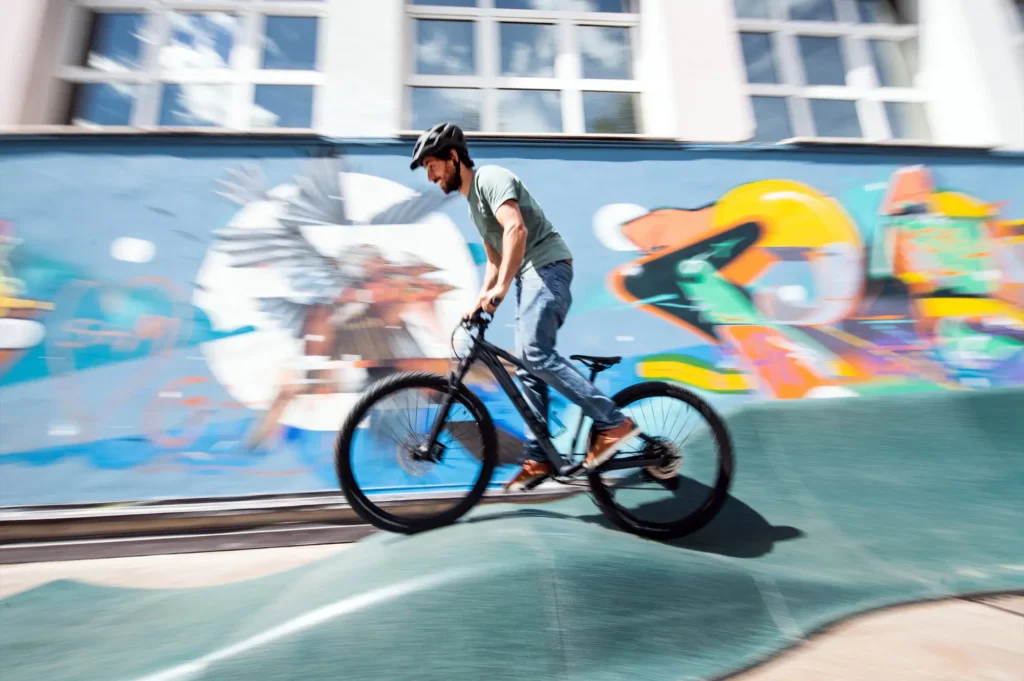 Pumptrack mit Mountainbikes, Scootern und Skateboards in Aktion